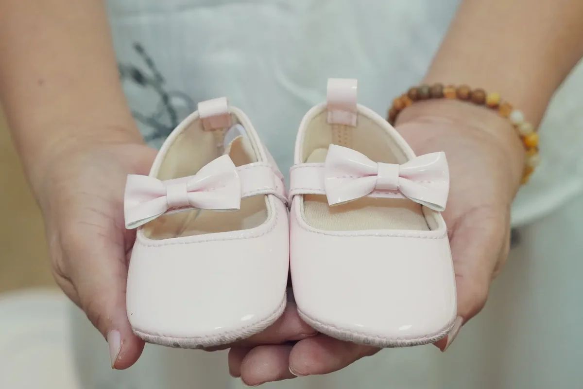Hands holding tiny pink baby shoes at a baby shower hosted at Price Creek Event Center near Cedar Rapids, Iowa.